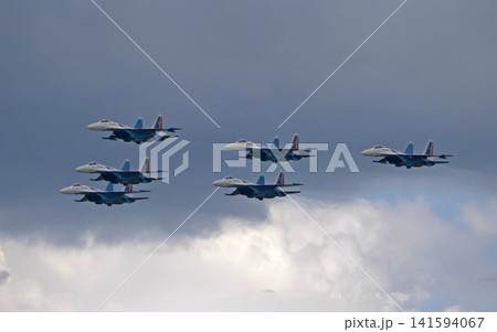 Russia Kubinka 12 April 2025. Russian Knights aerobatic team performing on Su-30SM and Su-35S fighter jets during an air show. Military aircraft in formation flight with smoke trails against blue sky 141594067