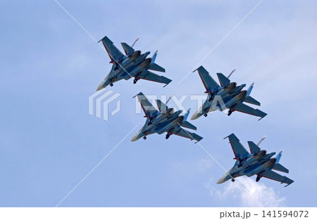 Russia Kubinka 12 April 2025. Russian Knights aerobatic team performing on Su-30SM and Su-35S fighter jets during an air show. Military aircraft in formation flight with smoke trails against blue sky 141594072