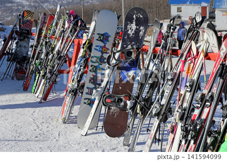 Russia Primorsky Krai Arsenyev 20 January 2026. Many skis and snowboards parked in ski rack at winter resort. Snow sports equipment storage on snowy day at mountain 141594099