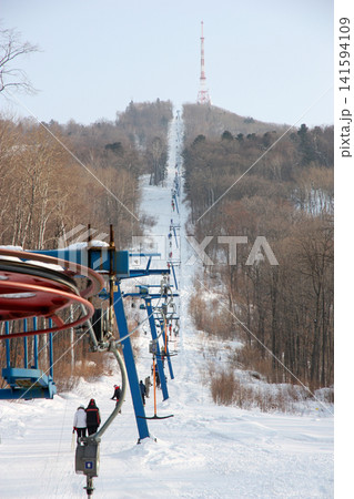 Russia Primorsky Krai Arsenyev 20 January 2026. Ski lift going up the mountain with TV tower on top. Winter sports tourism infrastructure at ski resort in Far East Russia Primorsky Krai Arsenyev 20 January 2026. Ski lift going up the mountain with TV tower on top. Winter sports tourism infrastructure at ski resort in Far East 141594109