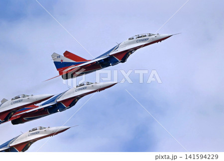 Russia Kubinka 12 April 2025. Strizhi aerobatic team performing on MiG-29 fighter jets during an air show. Russian military aircraft in formation flight with smoke trails against blue sky 141594229