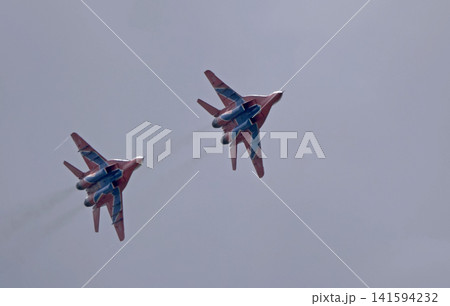 Russia Kubinka 12 April 2025. Strizhi aerobatic team performing on MiG-29 fighter jets during an air show. Russian military aircraft in formation flight with smoke trails against blue sky Russia Kubinka 12 April 2025. Strizhi aerobatic team performing on MiG-29 fighter jets during an air show. Russian military aircraft in formation flight with smoke trails against blue sky 141594232