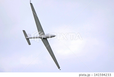 Russia 12 April 2025. Glider or sailplane in flight against blue sky. Lightweight aircraft without engine soaring in air. Aviation display at air show Russia 12 April 2025. Glider or sailplane in flight against blue sky. Lightweight aircraft without engine soaring in air. Aviation display at air show 141594233