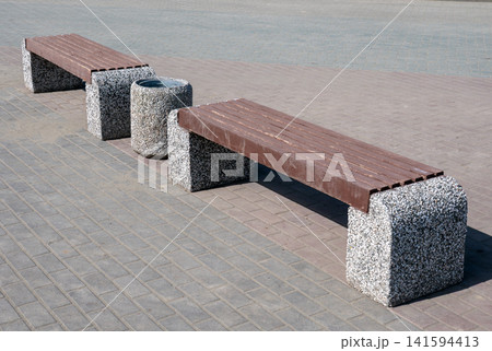 Two park benches with trash bin in urban park outdoor seating recreation area public space. Two park benches with trash bin in urban park outdoor seating recreation area public space. 141594413