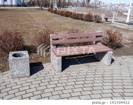 Park bench with trash bin in urban park outdoor seating recreation public space. Park bench with trash bin in urban park outdoor seating recreation public space. 141594422