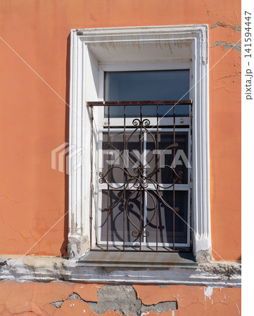 Window with decorative wrought iron grille architectural detail on building facade. Window with decorative wrought iron grille architectural detail on building facade. 141594447