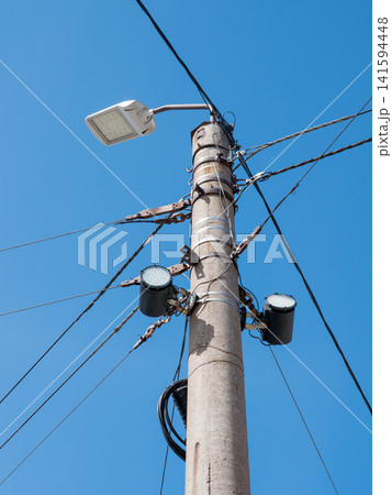 Street pole with lights junction box surveillance camera and cables against blue sky urban infrastructure security system. Street pole with lights junction box surveillance camera and cables against blue sky urban infrastructure security system. 141594448