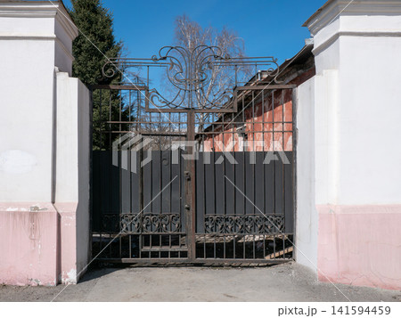 Old wrought iron rusty metal gates to courtyard vintage urban architecture detail. Old wrought iron rusty metal gates to courtyard vintage urban architecture detail. 141594459