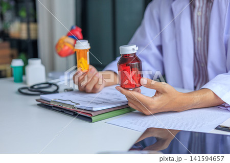 Healthcare professional reviewing patient medical records and verifying medication for heart disease in clinic. Healthcare professional reviewing patient medical records and verifying medication for heart disease in clinic. 141594657