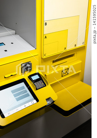 Yellow parcel locker kiosk with a touchscreen interface and card payment terminal illustrates contactless self service shipping. Yellow parcel locker kiosk with a touchscreen interface and card payment terminal illustrates contactless self service shipping. 141595025