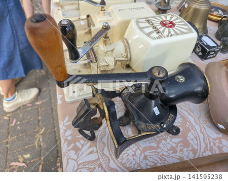 Xalo, Spain - June 20, 2026.Old mechanical cast iron Spong coffee bean grinder on a table at a vintage market with other items Xalo, Spain - June 20, 2026.Old mechanical cast iron Spong coffee bean grinder on a table at a vintage market with other items 141595238