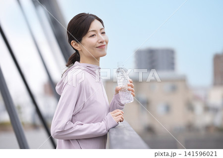 ウォーキング中にペットボトルの水を飲むミドル女性 ウォーキング中にペットボトルの水を飲むミドル女性 141596021