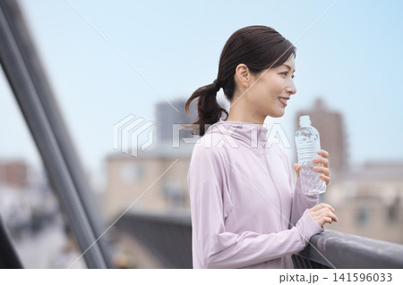 ウォーキング中にペットボトルの水を飲むミドル女性 141596033