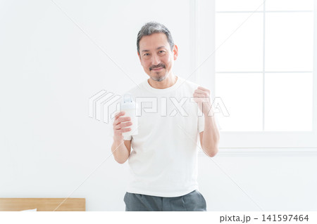 プロテインを持ってガッツポーズをする中高年男性 141597464