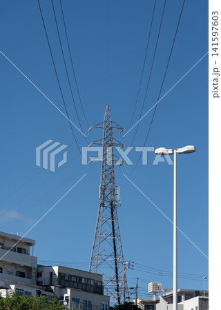 快晴の空で前後に伸びる送電線と街中の送電鉄塔 快晴の空で前後に伸びる送電線と街中の送電鉄塔 141597603