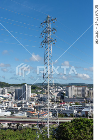快晴の空で左右に伸びる送電線と街中の送電鉄塔 141597608