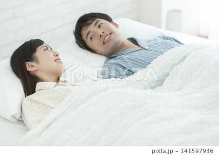 ベッドで話すパジャマ姿の夫婦 141597936