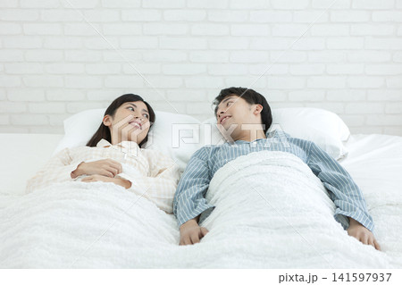 ベッドで話すパジャマ姿の夫婦 ベッドで話すパジャマ姿の夫婦 141597937