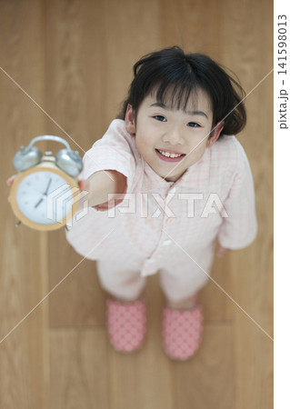 目覚し時計を持ったパジャマ姿の女の子 目覚し時計を持ったパジャマ姿の女の子 141598013