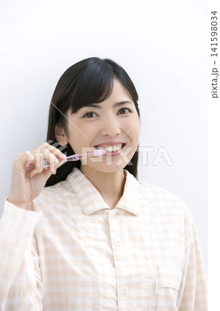 歯磨きをするパジャマ姿の女性 歯磨きをするパジャマ姿の女性 141598034