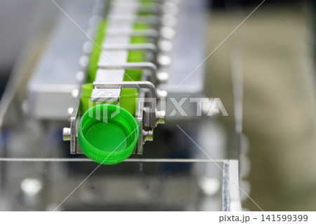 Green plastic bottle caps on conveyor belt after mass production process Green plastic bottle caps on conveyor belt after mass production process 141599399