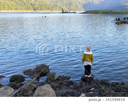 girl standing alone on the edge of the lake 141599819
