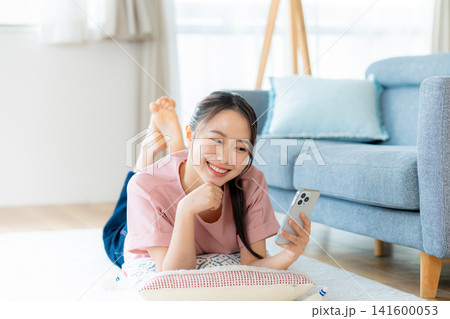 部屋でスマホを操作する若い女性 部屋でスマホを操作する若い女性 141600053