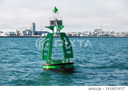 Green buoy with cone shaped top-mark float in front of urban skyline Green buoy with cone shaped top-mark float in front of urban skyline 141601457