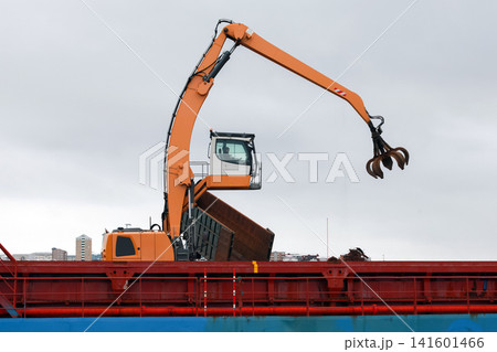 An orange material-handler excavator with a hydraulic grapple An orange material-handler excavator with a hydraulic grapple 141601466