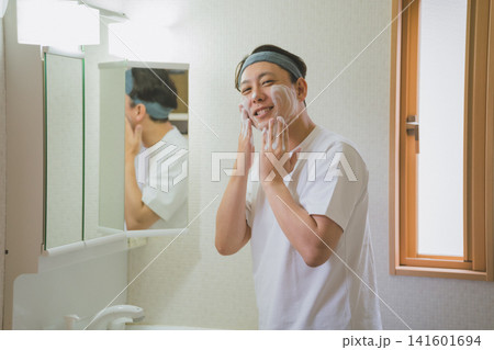 鏡の前でヘアバンドをして泡洗顔する40代男性 141601694