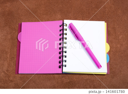 Open notebook with pink bookmark on a pink background 141601780