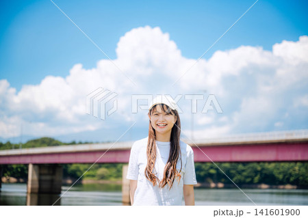 夏空の川辺で微笑む白キャップの女性 夏空の川辺で微笑む白キャップの女性 141601900