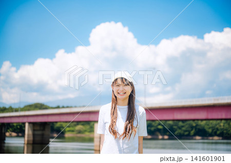 入道雲の下で微笑む白Tシャツの女性 入道雲の下で微笑む白Tシャツの女性 141601901