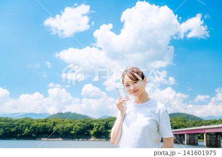 夏の川辺で水分補給する女性 141601975