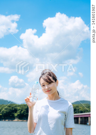 入道雲の下で水分補給する白Tシャツの女性 入道雲の下で水分補給する白Tシャツの女性 141601987
