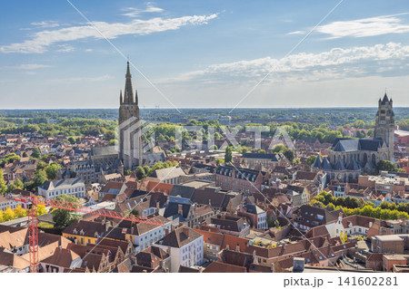 Bruges town in Belgium, Europe. Panoramic Aerial View of a Historic European Cityscape with Ancient Towers and Red Rooftops Under a Bright Blue Sky Bruges town in Belgium, Europe. Panoramic Aerial View of a Historic European Cityscape with Ancient Towers and Red Rooftops Under a Bright Blue Sky 141602281