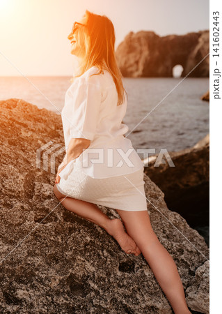 Woman coast sunset enjoys a peaceful moment on rocky cliffs by the sea during golden hour Woman coast sunset enjoys a peaceful moment on rocky cliffs by the sea during golden hour 141602443