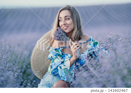 Lavender woman field smiling woman holding lavender bouquet in a purple meadow at sunset with a straw hat on her back. Lavender woman field smiling woman holding lavender bouquet in a purple meadow at sunset with a straw hat on her back. 141602467