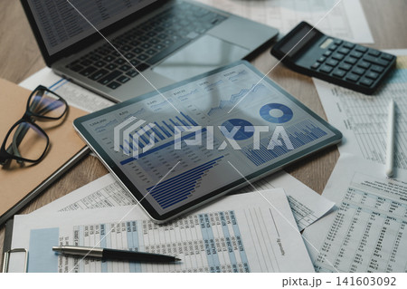 business project finance investment dashboard beside laptop, calculator, eyeglasses, pen, printed reports supporting financial analysis, document reporting, business finance workflow. business project finance investment dashboard beside laptop, calculator, eyeglasses, pen, printed reports supporting financial analysis, document reporting, business finance workflow. 141603092