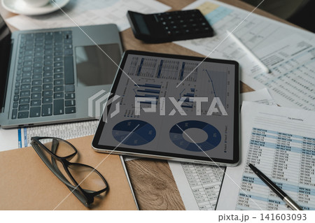 Accountant financial data spreadsheets charts laptop, calculator, eyeglasses, printed spreadsheets, supporting financial data analysis, document review, accounting reporting workflow. Accountant financial data spreadsheets charts laptop, calculator, eyeglasses, printed spreadsheets, supporting financial data analysis, document review, accounting reporting workflow. 141603093