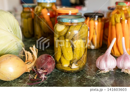 Assorted pickled vegetables in jars with fresh onions and garlic on a rustic kitchen counter. National Pickle Day Assorted pickled vegetables in jars with fresh onions and garlic on a rustic kitchen counter. National Pickle Day 141603603