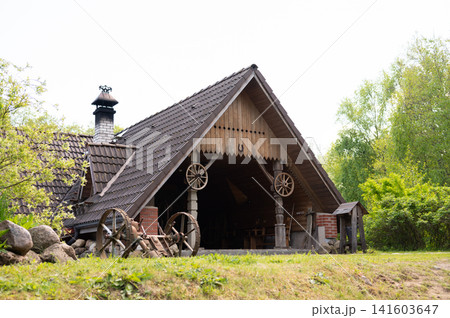 Rustic wooden barn in lush countryside with wagon wheels Rustic wooden barn in lush countryside with wagon wheels 141603647