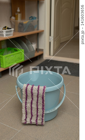 Empty blue bucket with striped cloth in tiled laundry room Empty blue bucket with striped cloth in tiled laundry room 141603656