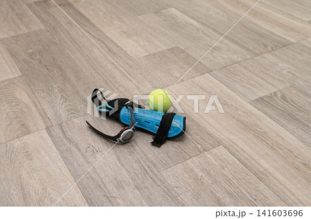 Tennis ball and blue wrist straps on wooden floor Tennis ball and blue wrist straps on wooden floor 141603696