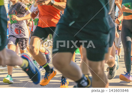 Runners compete in road race as crowded field moves along city course during public sports event. Runners show participation, endurance, fitness, competition, community athletics Runners compete in road race as crowded field moves along city course during public sports event. Runners show participation, endurance, fitness, competition, community athletics 141603846