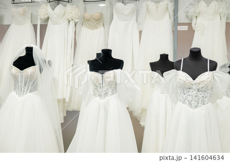 Elegant white bridal gowns on mannequins in bridal boutique display Elegant white bridal gowns on mannequins in bridal boutique display 141604634