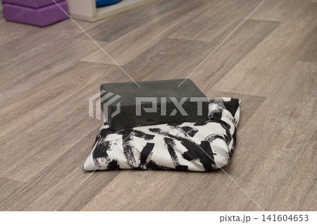 Yoga block on abstract cushion on wooden floor Yoga block on abstract cushion on wooden floor 141604653
