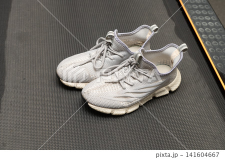 Gray athletic sneakers on black mat in gym environment 141604667