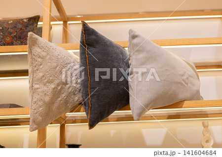 Textured decorative pillows arranged on wooden store shelf Textured decorative pillows arranged on wooden store shelf 141604684