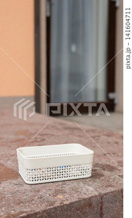Rectangular white woven basket on stone surface outdoors 141604711